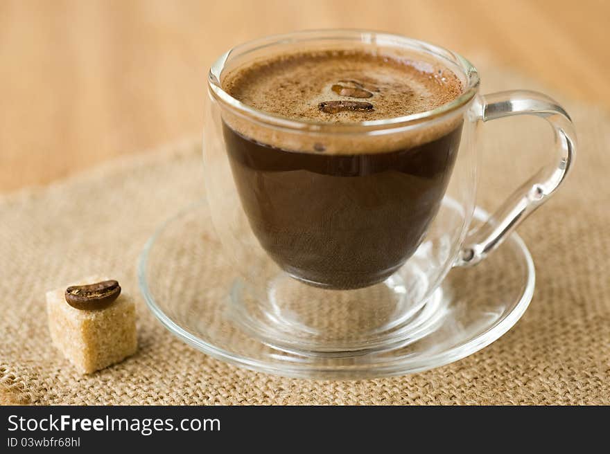 Cup of coffee, sugar, coffee beans on a napkin of burlap