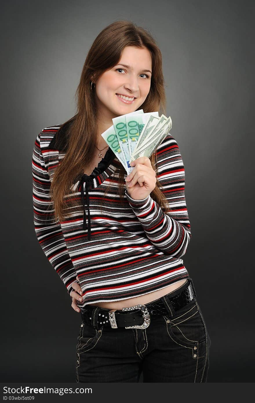 Pretty woman smiling while holding fan made of money  on a  grey background. Pretty woman smiling while holding fan made of money  on a  grey background