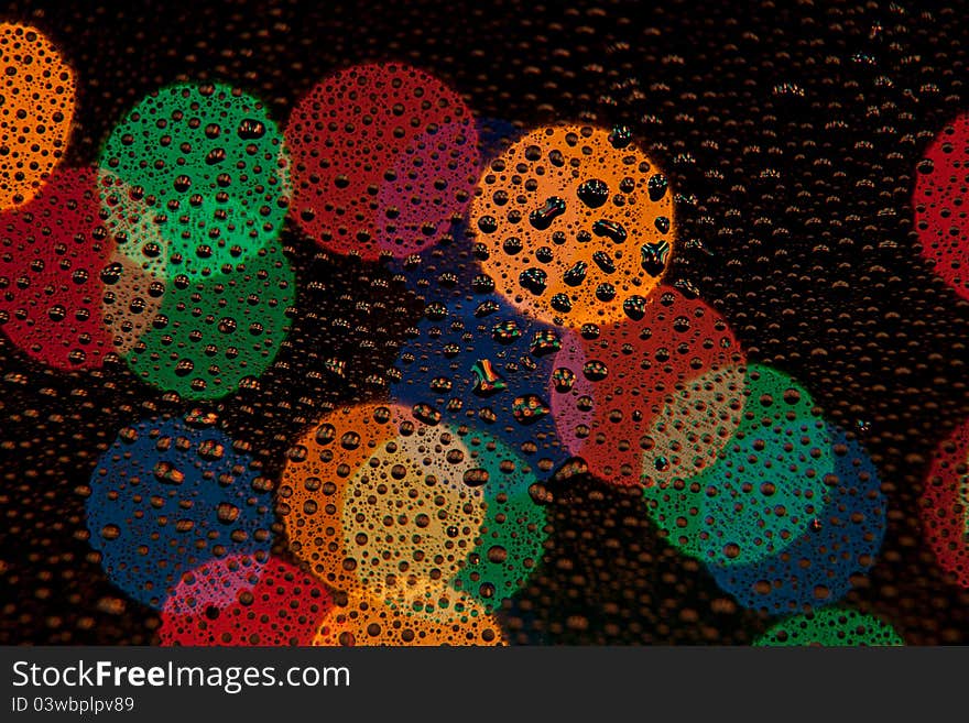 Color Bokeh on dark background with drops in the foreground. Color Bokeh on dark background with drops in the foreground.