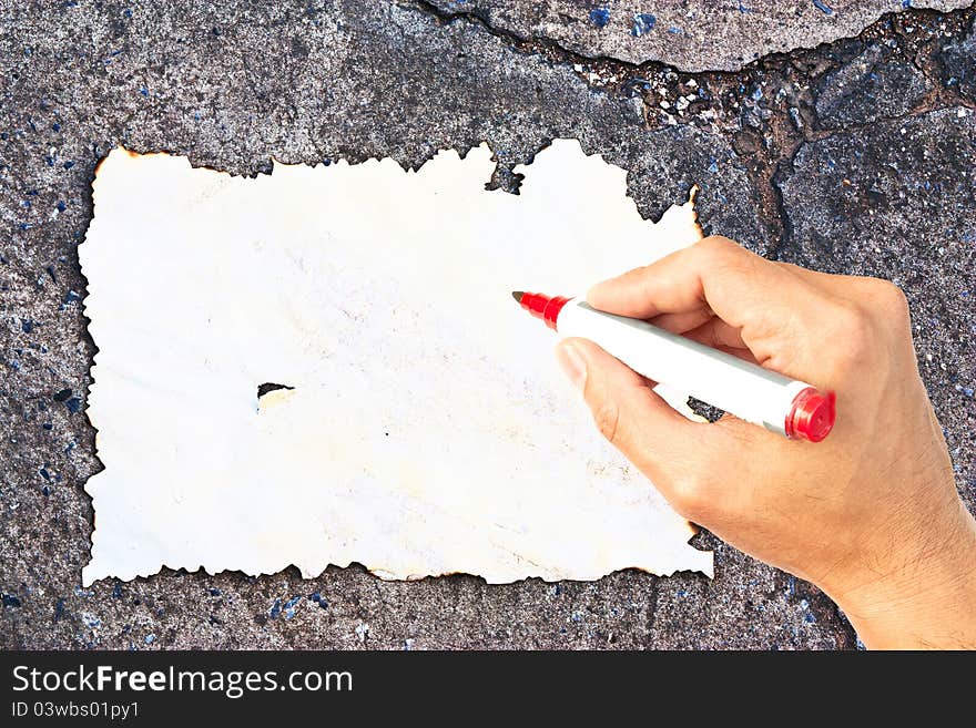 Writing hand at burn paper on concrete background