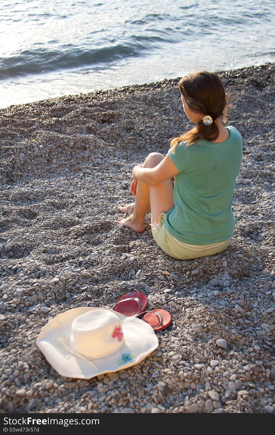 The girl, hat and flip-flops on the stones outdoors shooting