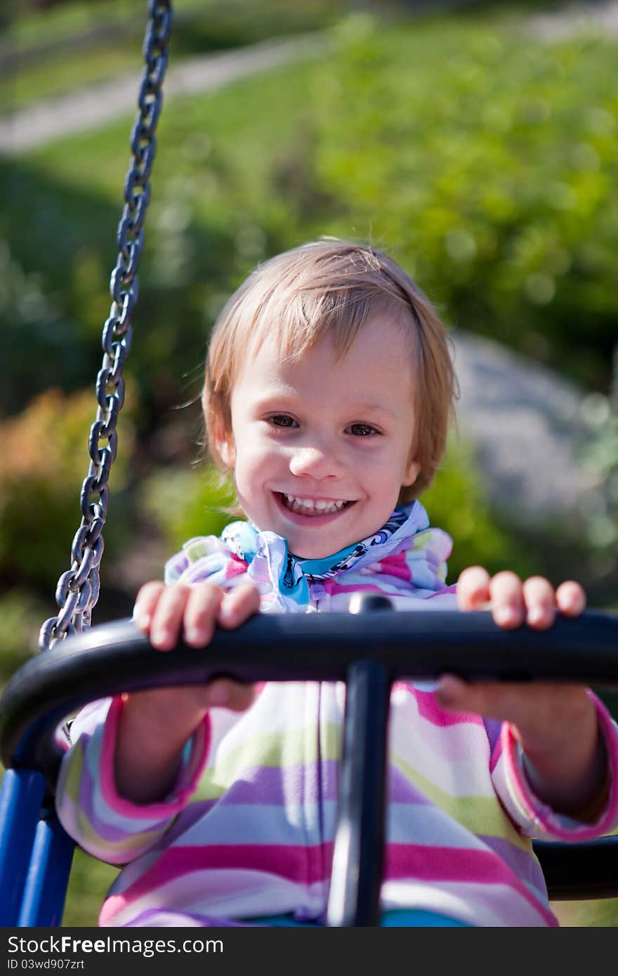 Portrait of smiling little girl on swing playground outdoors - looking at the camera. Portrait of smiling little girl on swing playground outdoors - looking at the camera