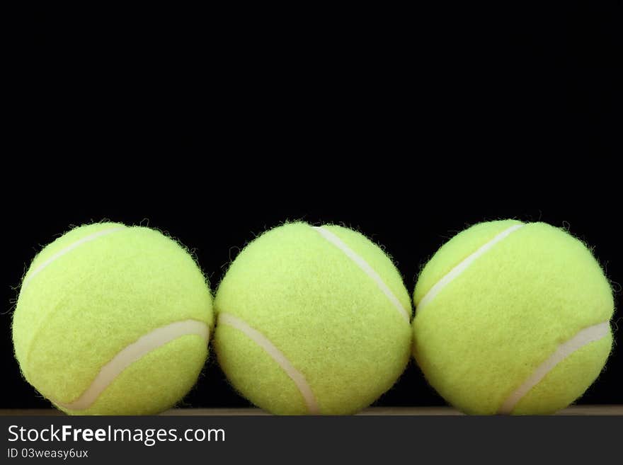 Three tennis balls on black background