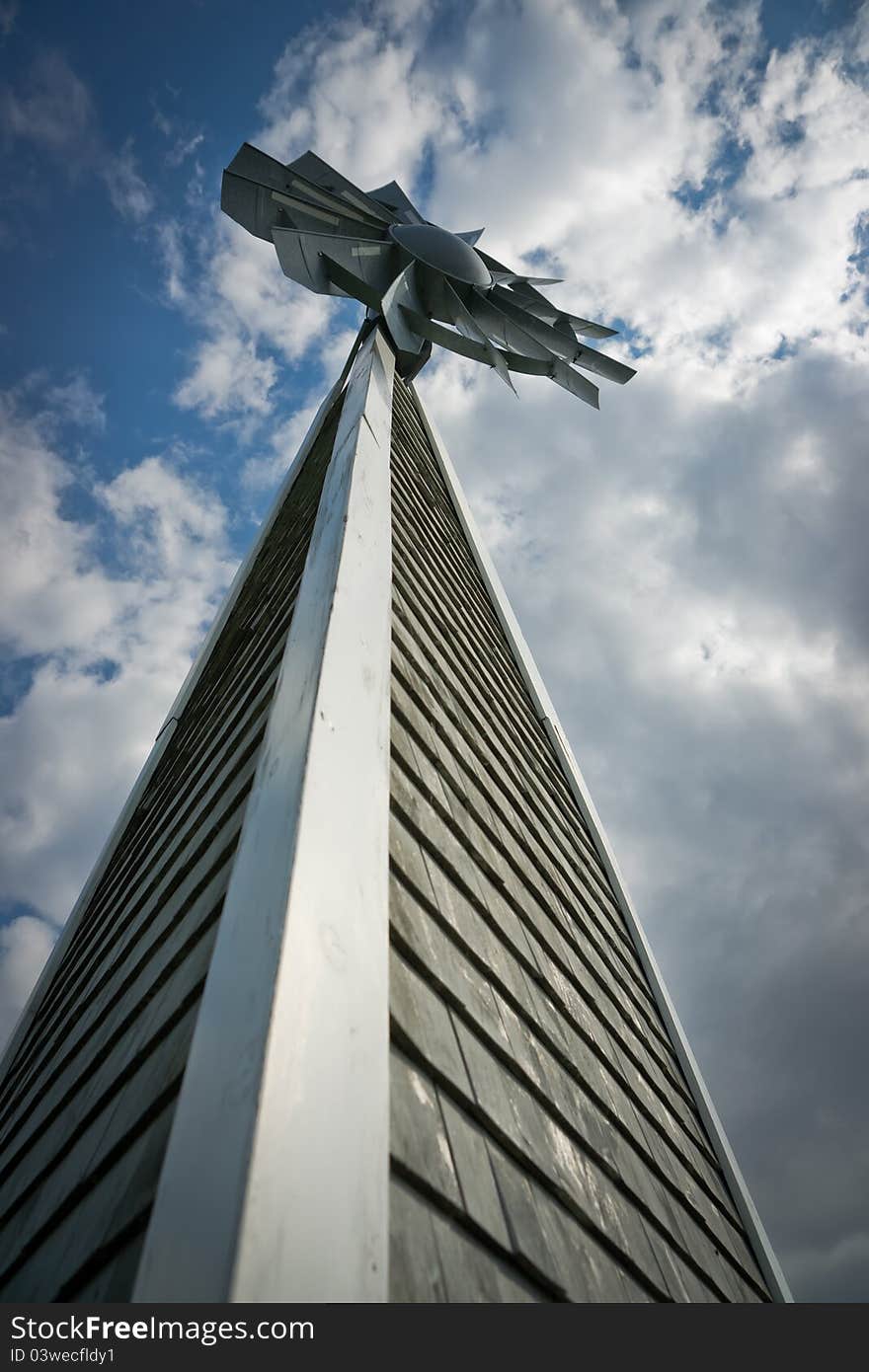 Unusual perspective of a tall, wooden windmill under a cloudy blue sky. Unusual perspective of a tall, wooden windmill under a cloudy blue sky