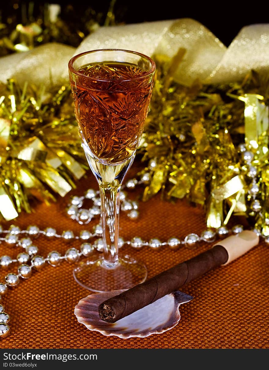 Crystal glass with brandy, cigars and Christmas decorations on a black background