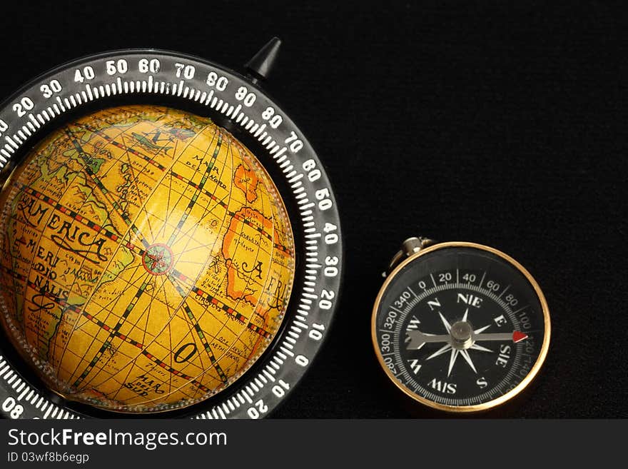 Globe and a compass on black background