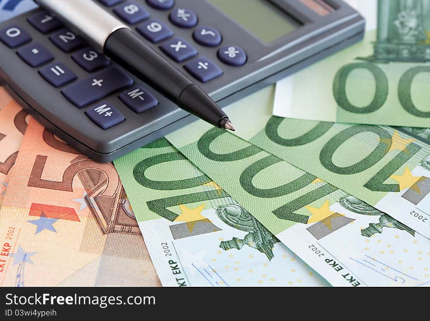 Business concept. Closeup of ball pen and calculator on european currency background. Business concept. Closeup of ball pen and calculator on european currency background