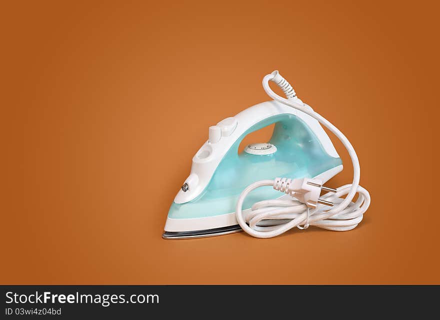 New modern electric iron with cable on nice brown background