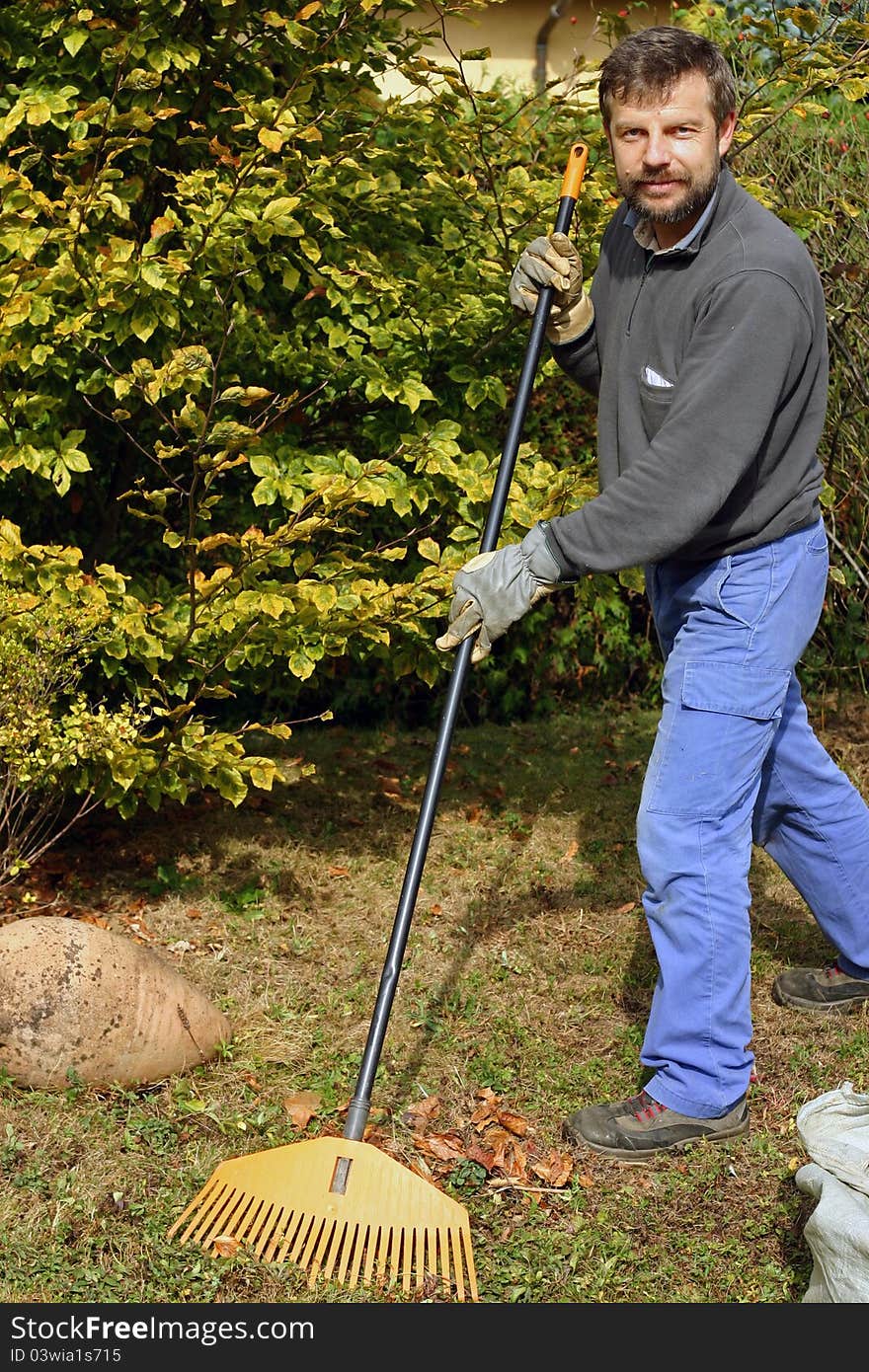 Likeable gardener cleaning outdoor from autumn leaves. Likeable gardener cleaning outdoor from autumn leaves