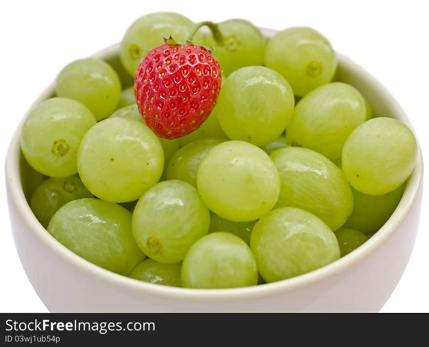 White cup filled with grapes and a strawberry. White cup filled with grapes and a strawberry