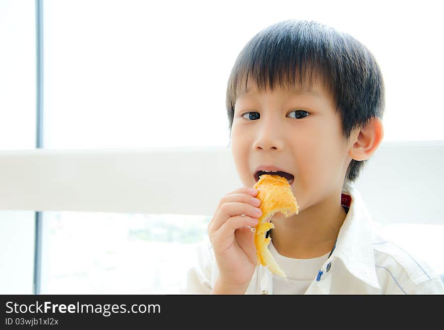 Asian boy eating a piece of pie and look at camera