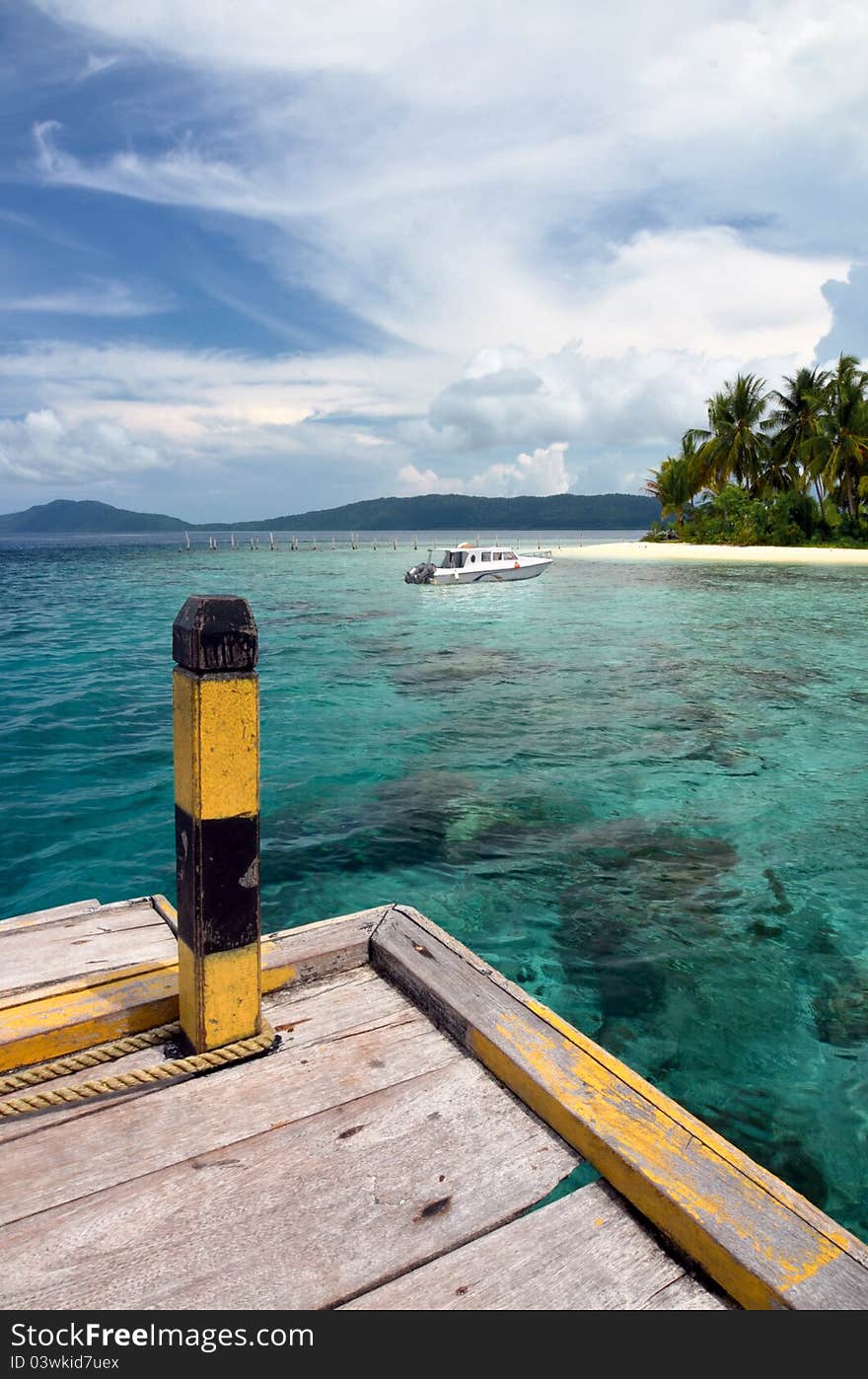 A boat docks in a tropical island. This landscape picture taken in Raja Ampat Island, papua, Indonesia. One of the most beautiful place on earth for diving and sightseeing. A boat docks in a tropical island. This landscape picture taken in Raja Ampat Island, papua, Indonesia. One of the most beautiful place on earth for diving and sightseeing.