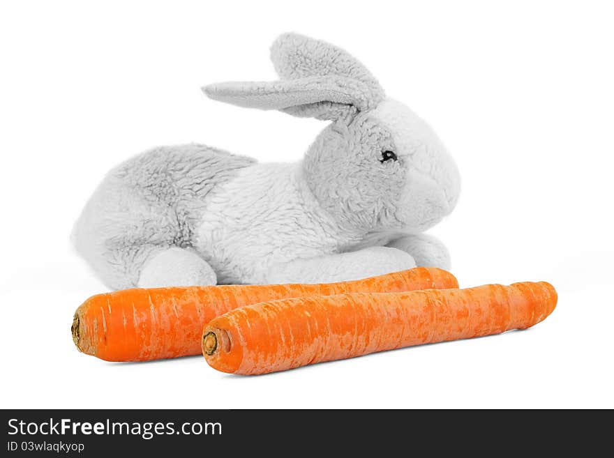 Carrots and a toy rabbit on a white background