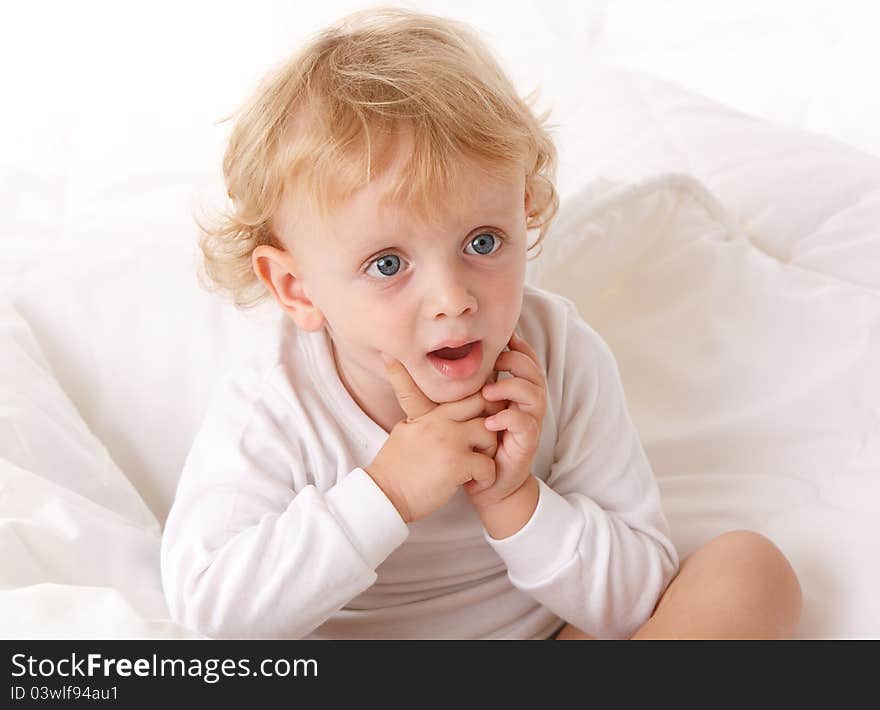 Little boy sitting on a white bed. Little boy sitting on a white bed