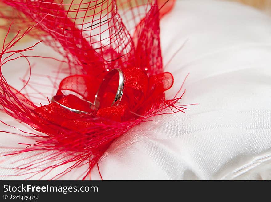 Cushion with wedding gold rings in red feathers. Left position. Cushion with wedding gold rings in red feathers. Left position