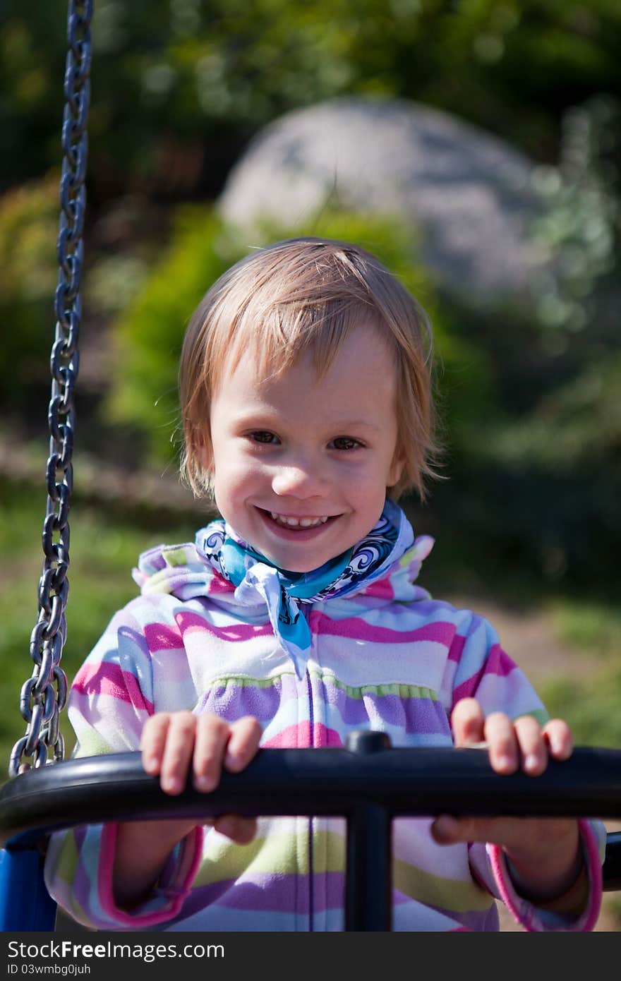 Portrait of smiling little girl on swing playground outdoors - looking at the camera. Portrait of smiling little girl on swing playground outdoors - looking at the camera