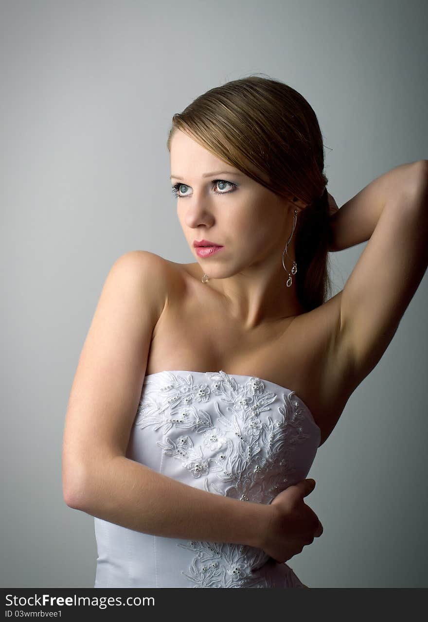 Beautiful charming young woman in white corset on a gray background