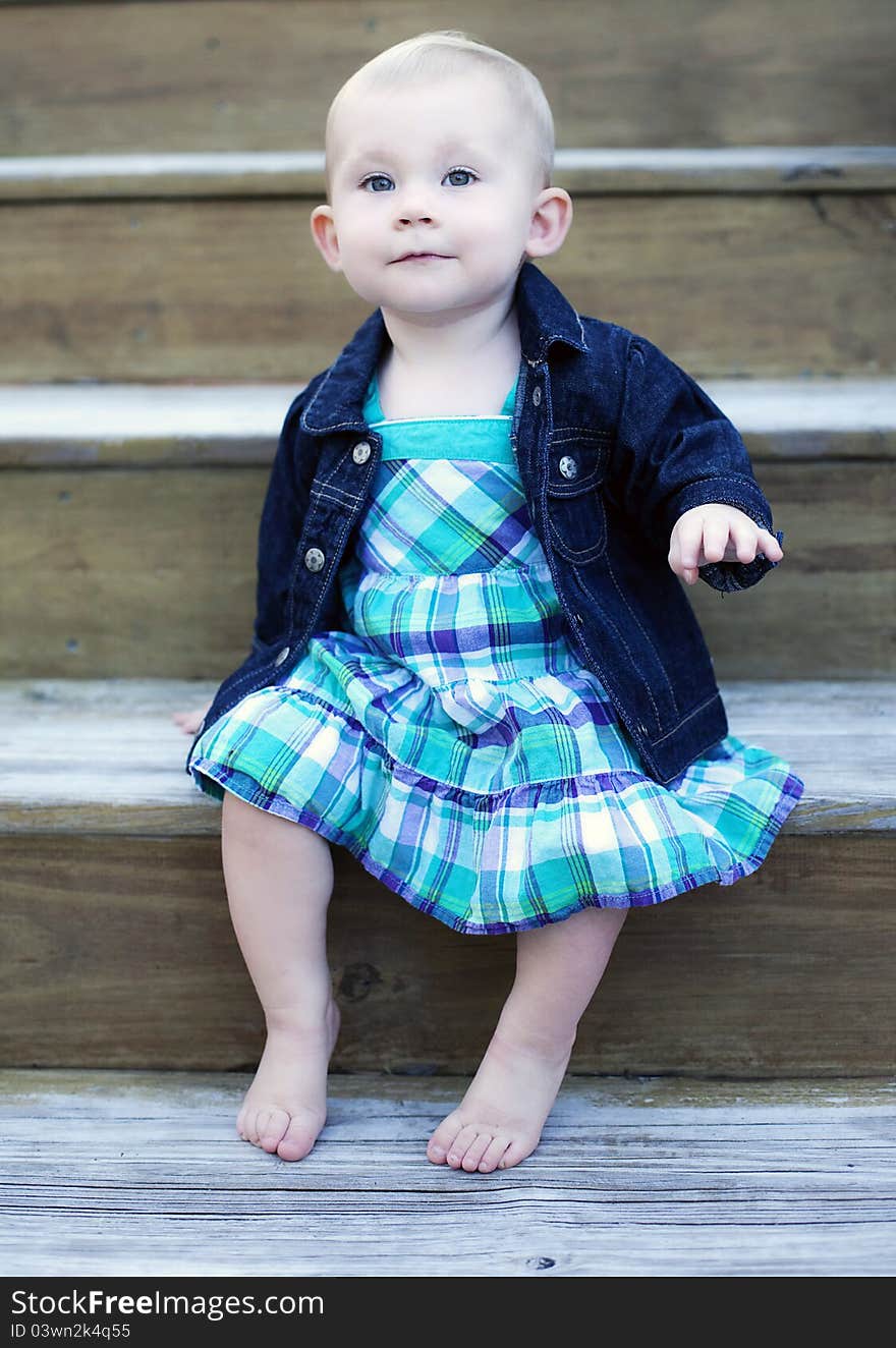 A one year old baby girl sitting on stairs. A one year old baby girl sitting on stairs.