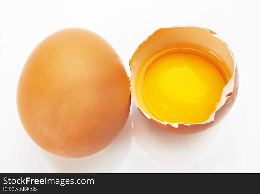 Two brown eggs on a white background. One egg is broken.