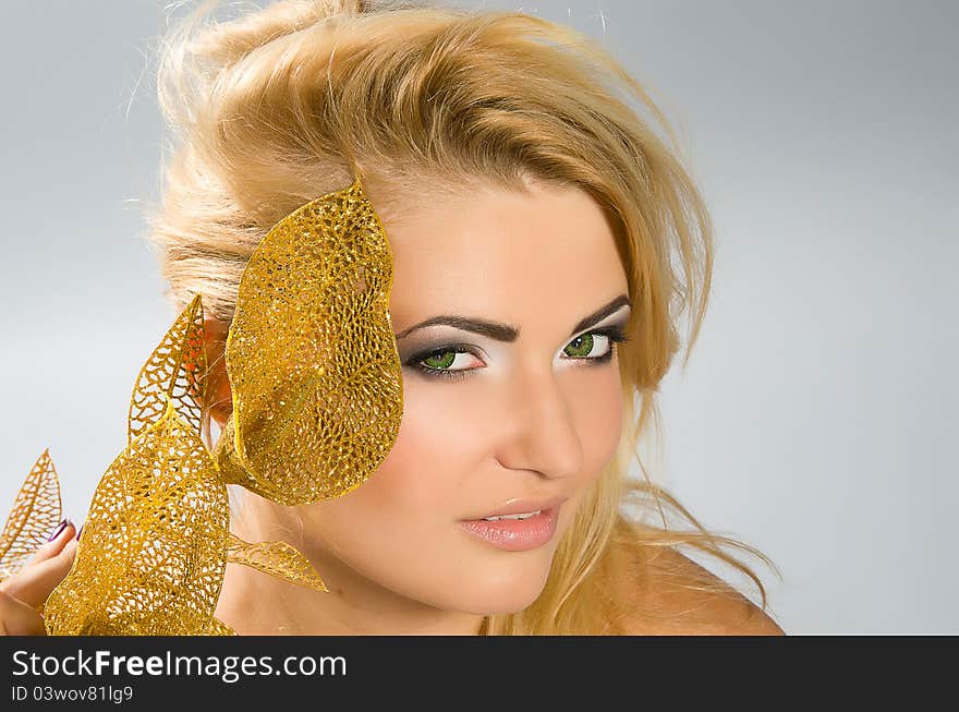 Beautiful green-eyed girl with blonde hair and professional make-up holding artificial golden calla lily. Beautiful green-eyed girl with blonde hair and professional make-up holding artificial golden calla lily