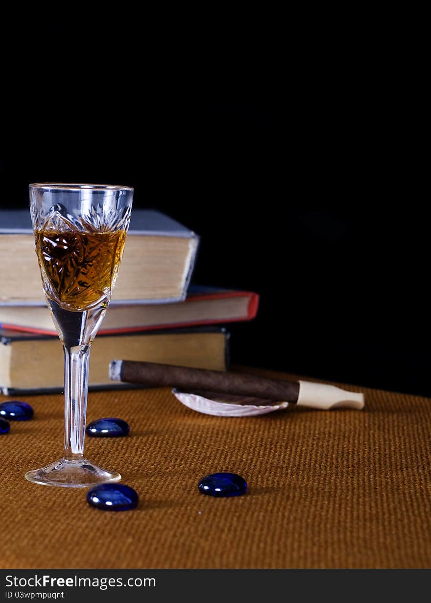 Crystal glass with cognac and cigar on the green book. Crystal glass with cognac and cigar on the green book.