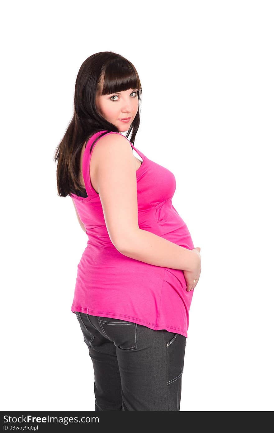 Pretty black-haired pregnant woman wearing bright pink dress holding her belly. Pretty black-haired pregnant woman wearing bright pink dress holding her belly