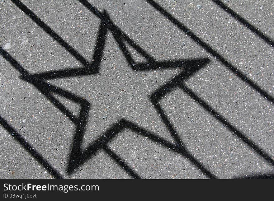 Black pentagonal starlike shadow on the pavement. Black pentagonal starlike shadow on the pavement