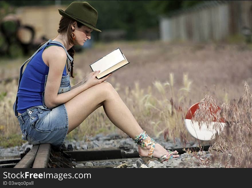 Portrait of a beautifully woman in late spring sun sitting on railway and reading. Portrait of a beautifully woman in late spring sun sitting on railway and reading