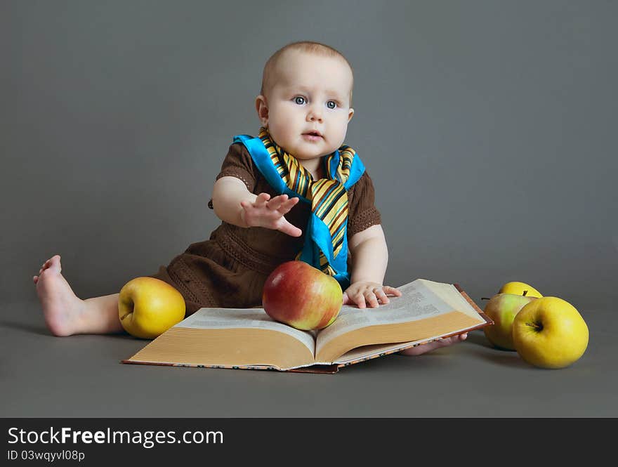 Portrait of the child on a gray background with the book and apples. Portrait of the child on a gray background with the book and apples