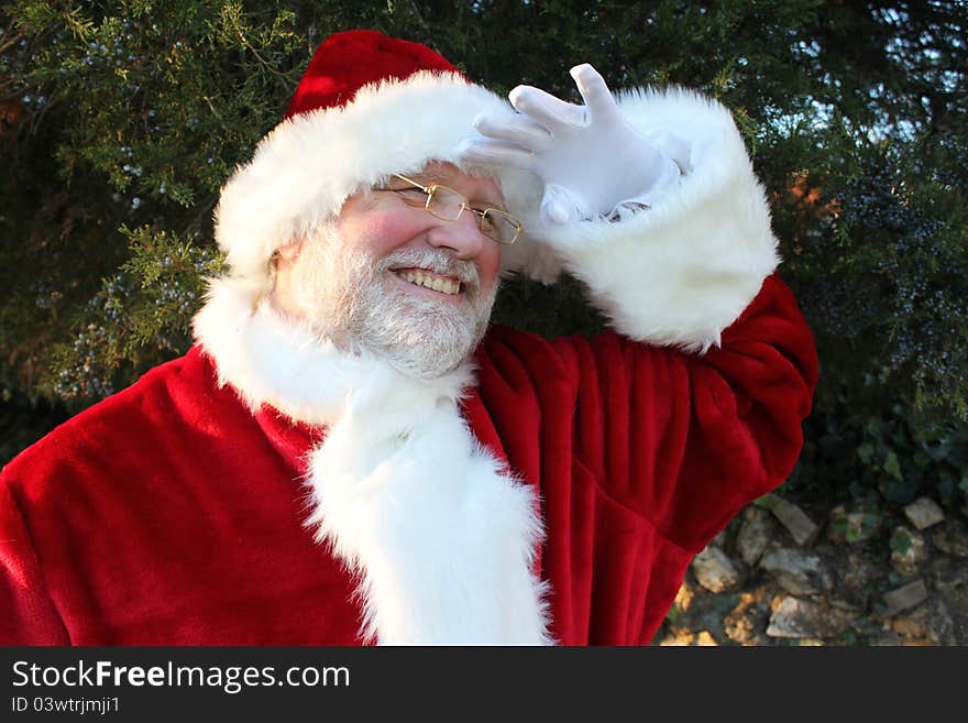 Smiling Santa holding his gloved hand over his eyes as he peers into the distance. Smiling Santa holding his gloved hand over his eyes as he peers into the distance.