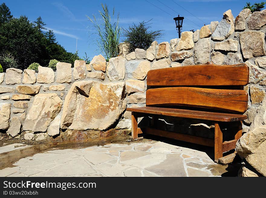 Wooden bench with a stone wall in background