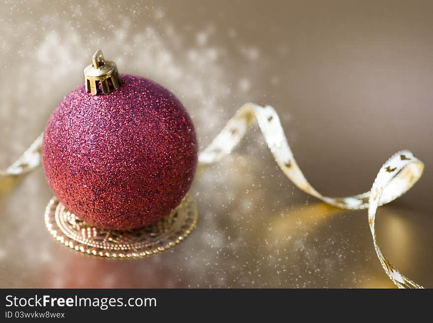 Christmas ball with gold ribbon bow with snow