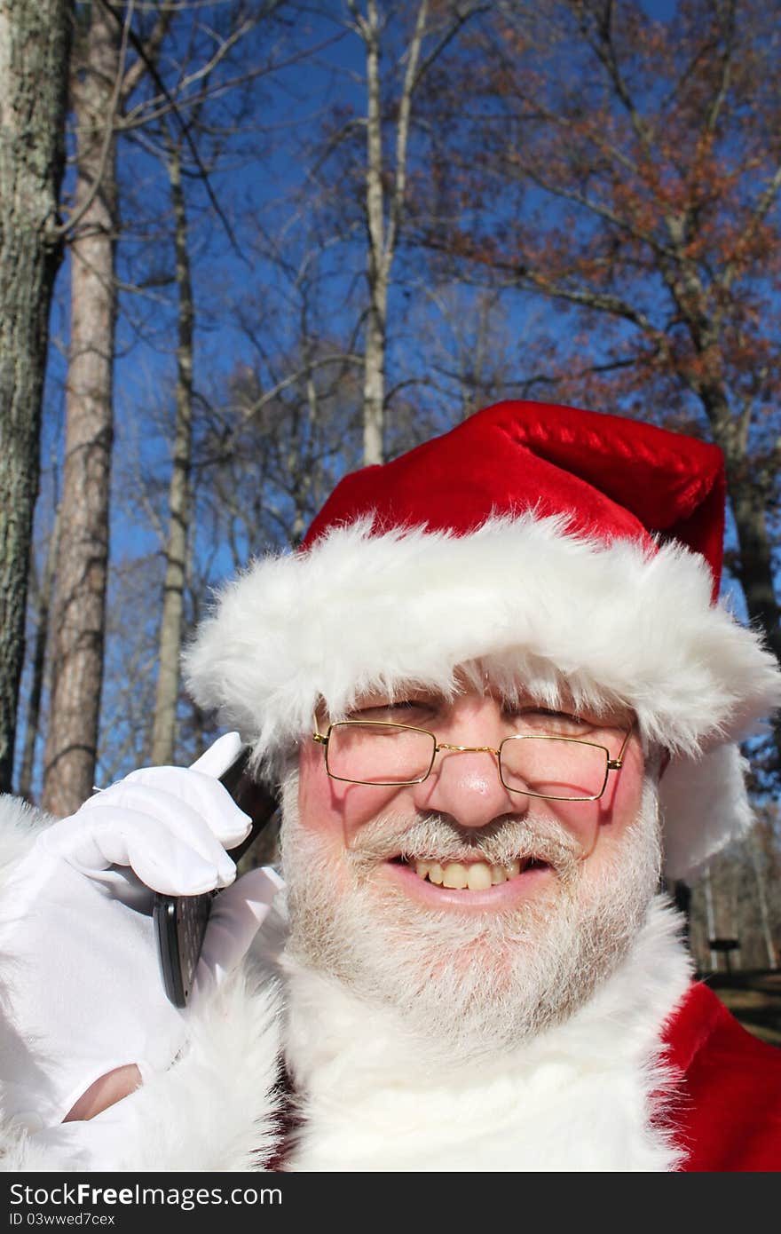 Santa making a call on his cell phone in an outdoor setting. Santa making a call on his cell phone in an outdoor setting.