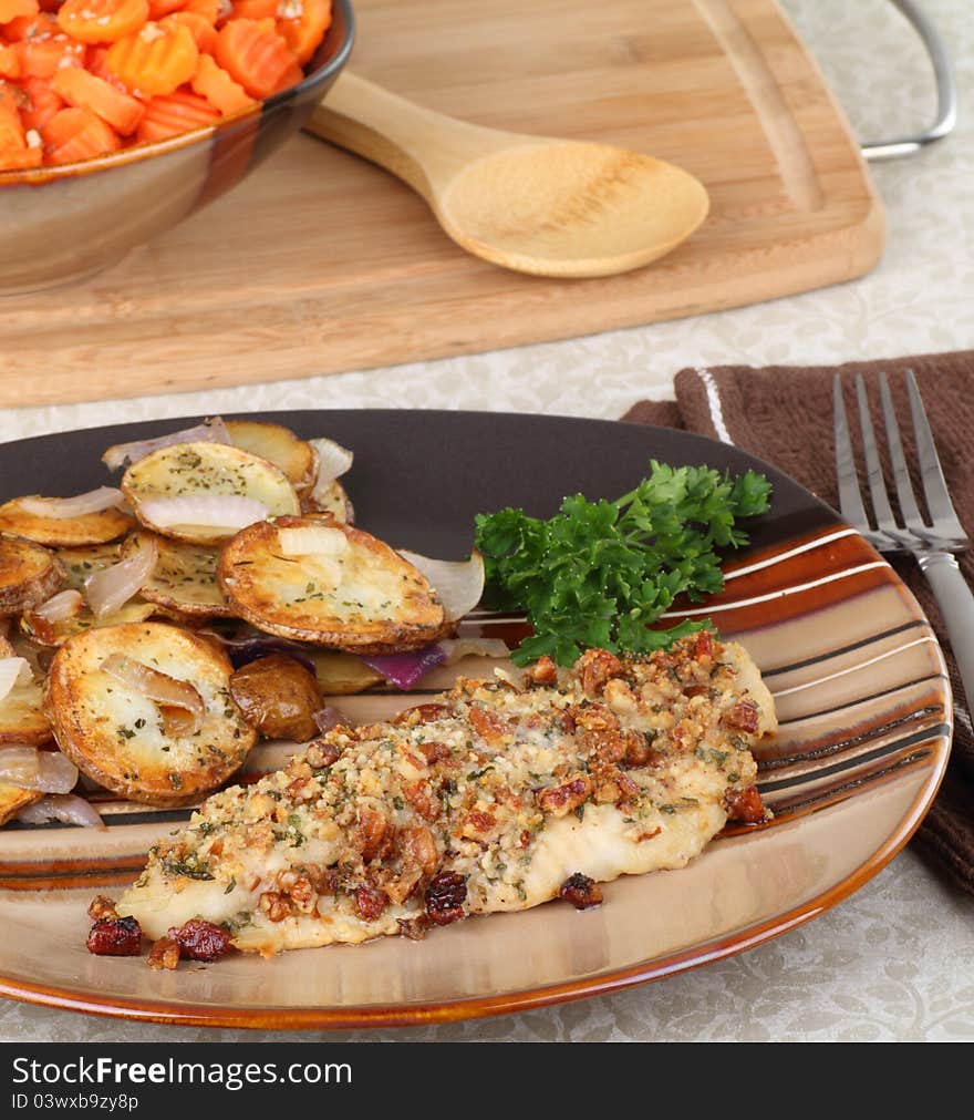 Cashew catfish fillet with potatoes and bowl of carrots in background. Cashew catfish fillet with potatoes and bowl of carrots in background