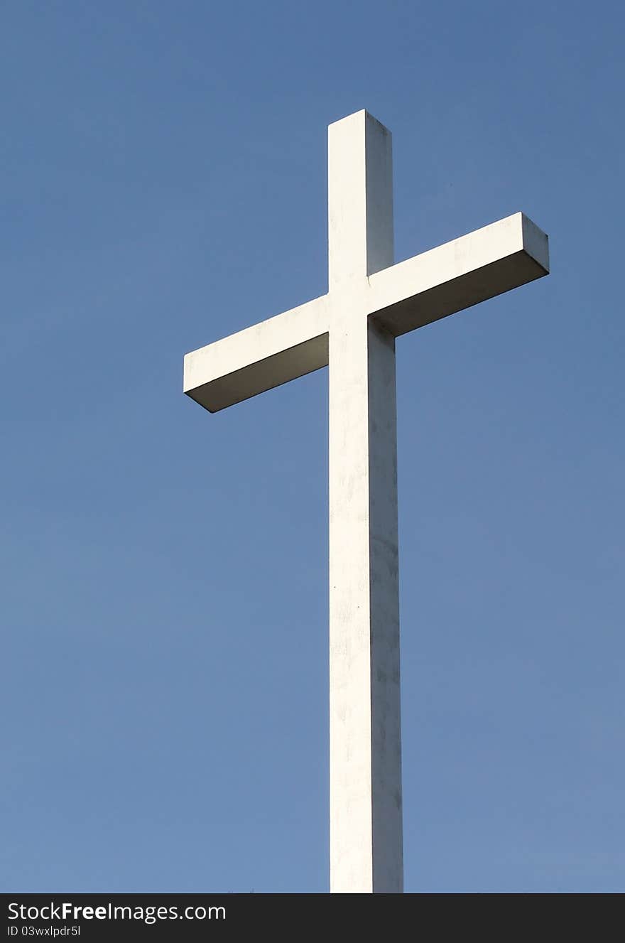 A white Christian cross stands out  against a deep blue blue sky. A white Christian cross stands out  against a deep blue blue sky.