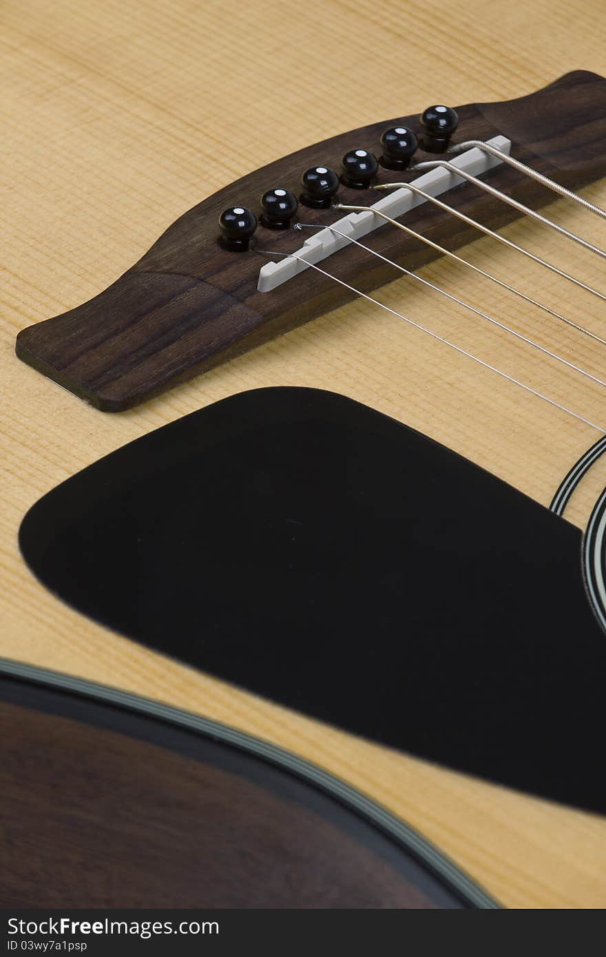 Closeup view of guitar saddle, bridge, and pick guard. Closeup view of guitar saddle, bridge, and pick guard