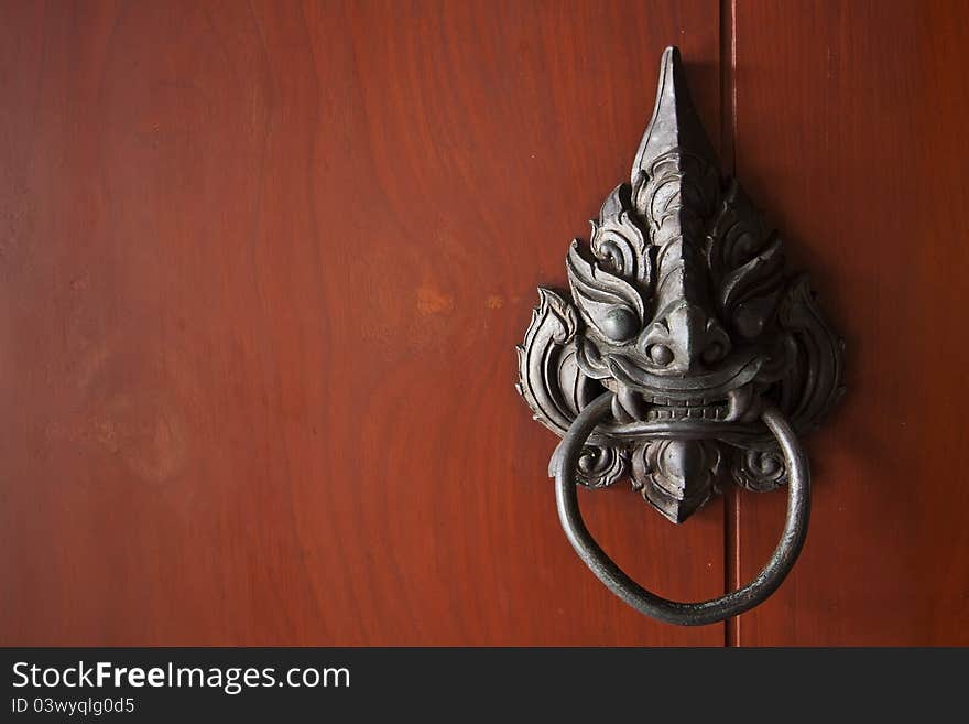 Antique door knocker in red wood background. Antique door knocker in red wood background.