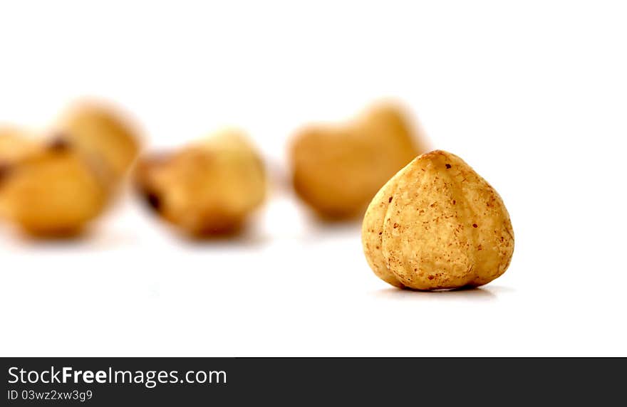 A hazelnut, stripped from its hard shell, with other hazelnuts in the background. A hazelnut, stripped from its hard shell, with other hazelnuts in the background