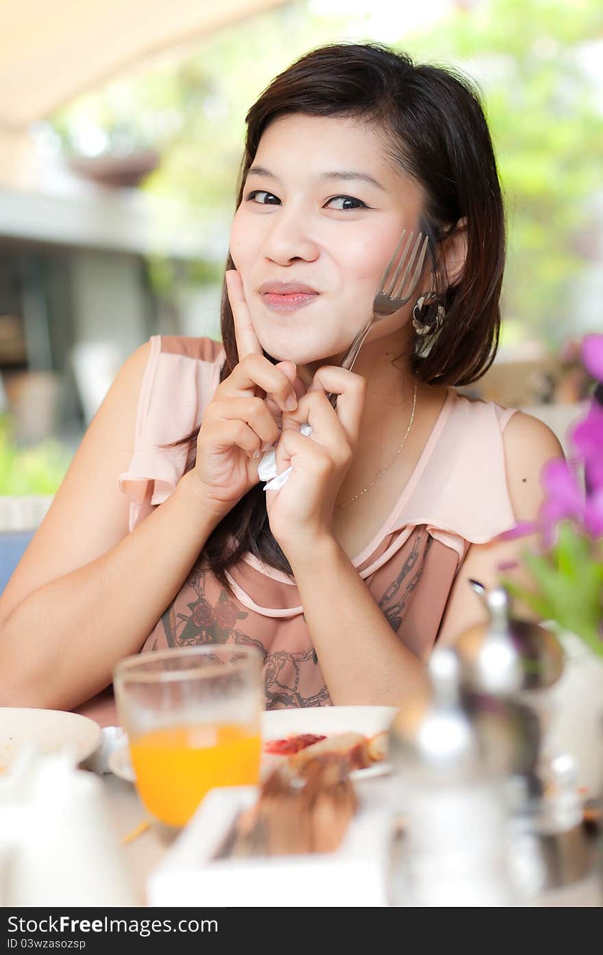 Beautiful girl holding fork and enjoy her food and look at camera