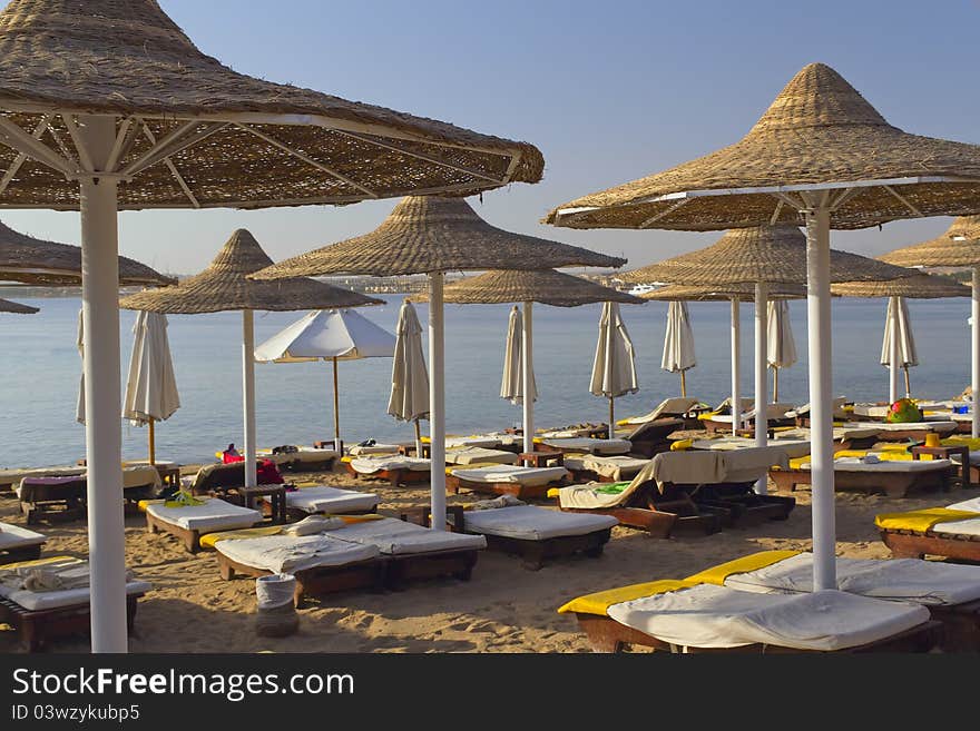 Deck chairs under an umbrella on a beach in the hot afternoon sun (Red Sea, Egypt). Deck chairs under an umbrella on a beach in the hot afternoon sun (Red Sea, Egypt)