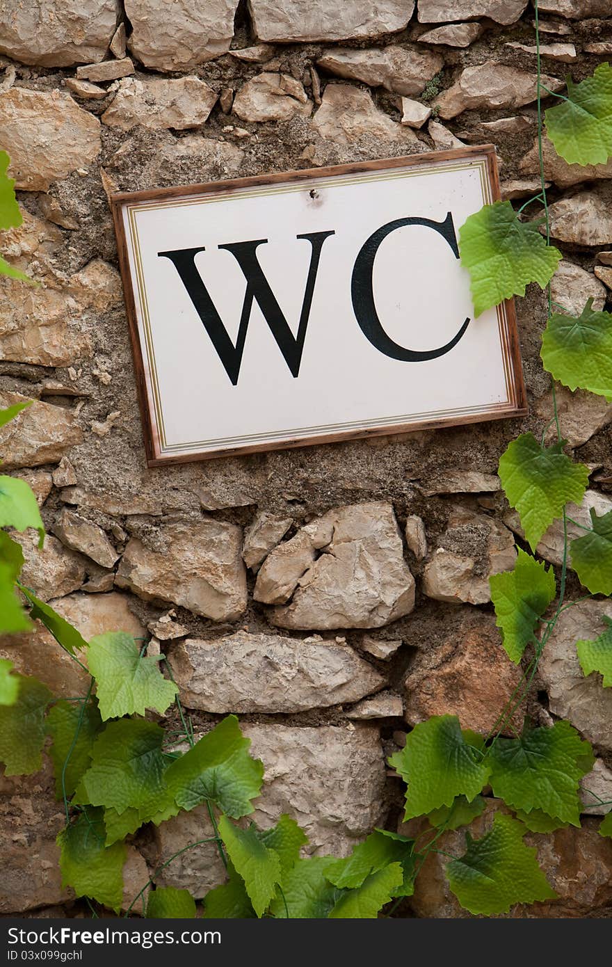 Guide to the bathroom, attached to an old stone wall. Guide to the bathroom, attached to an old stone wall