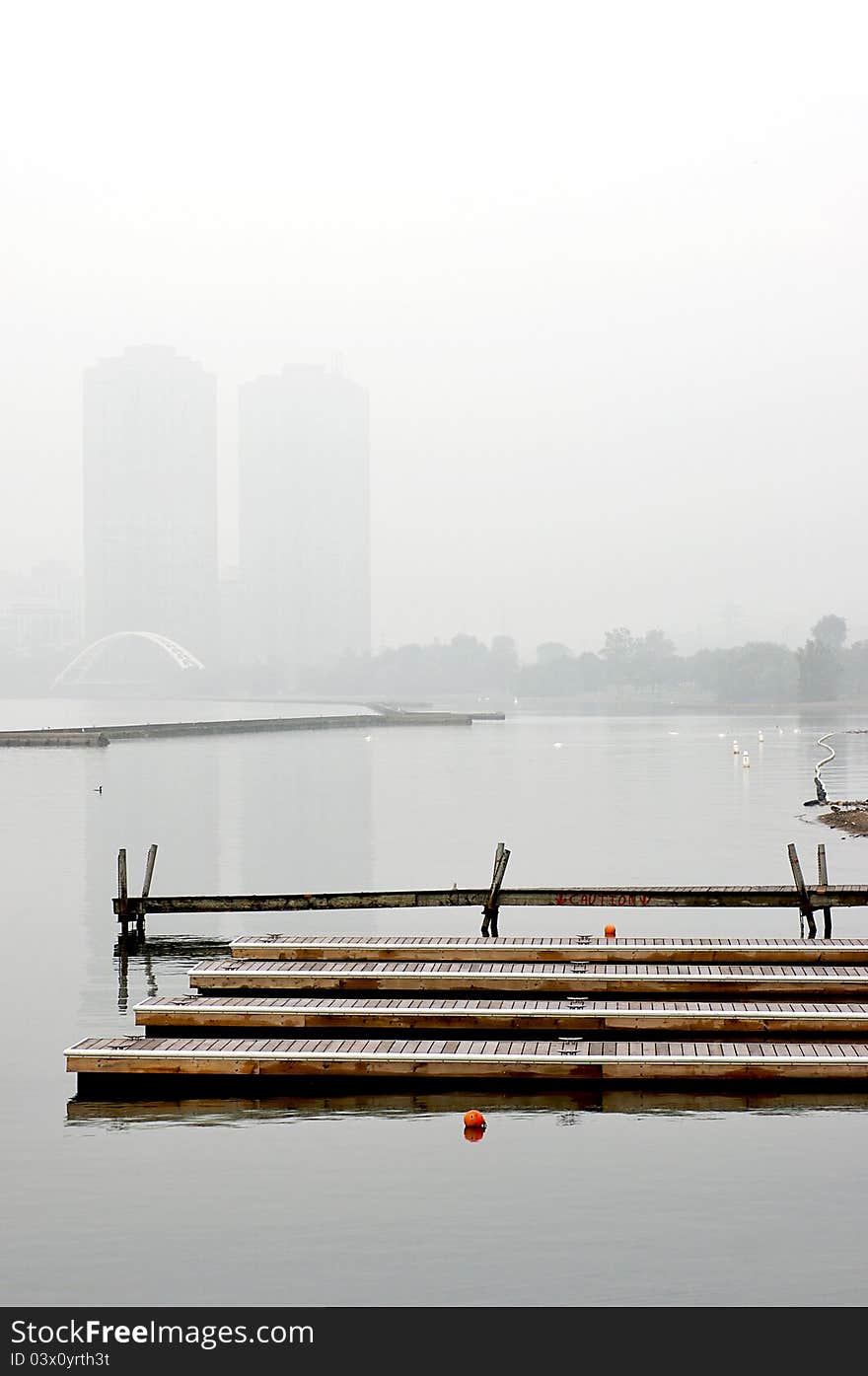 Floating docks are visible through the mist surrounding Sunnyside Beach on Lake Ontario in downtown Toronto. The Pierre Elliott Trudeau pedestrian bridge is visible in the distance - part of the Martin Goodman Waterfront Trail. Floating docks are visible through the mist surrounding Sunnyside Beach on Lake Ontario in downtown Toronto. The Pierre Elliott Trudeau pedestrian bridge is visible in the distance - part of the Martin Goodman Waterfront Trail.