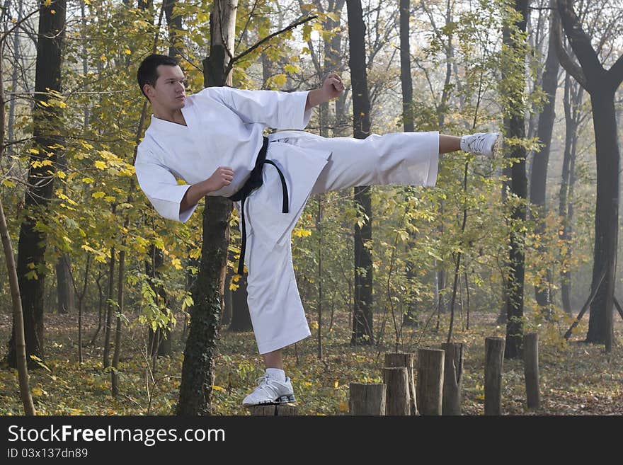 Man wearing Gi (Karate uniform) and black belt shown in a kick. Man wearing Gi (Karate uniform) and black belt shown in a kick