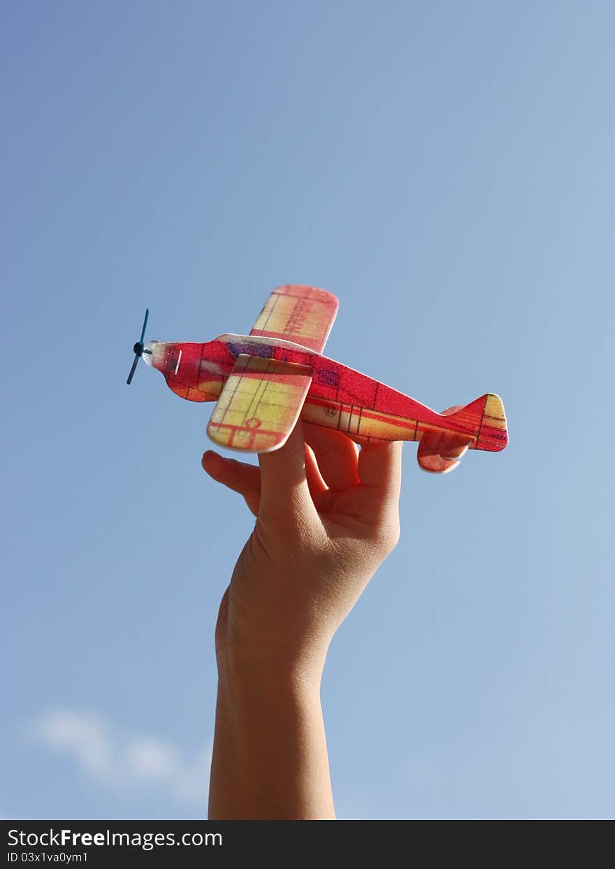 A positive image of someone playing with a toy plane made out of polystyrene with a sky as background. The light, sky and color of plane contribute to a positive feeling. A positive image of someone playing with a toy plane made out of polystyrene with a sky as background. The light, sky and color of plane contribute to a positive feeling.