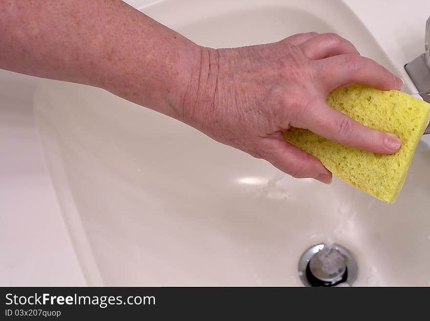 A hand holding a sponge doing a daily housekeeping chore. A hand holding a sponge doing a daily housekeeping chore.