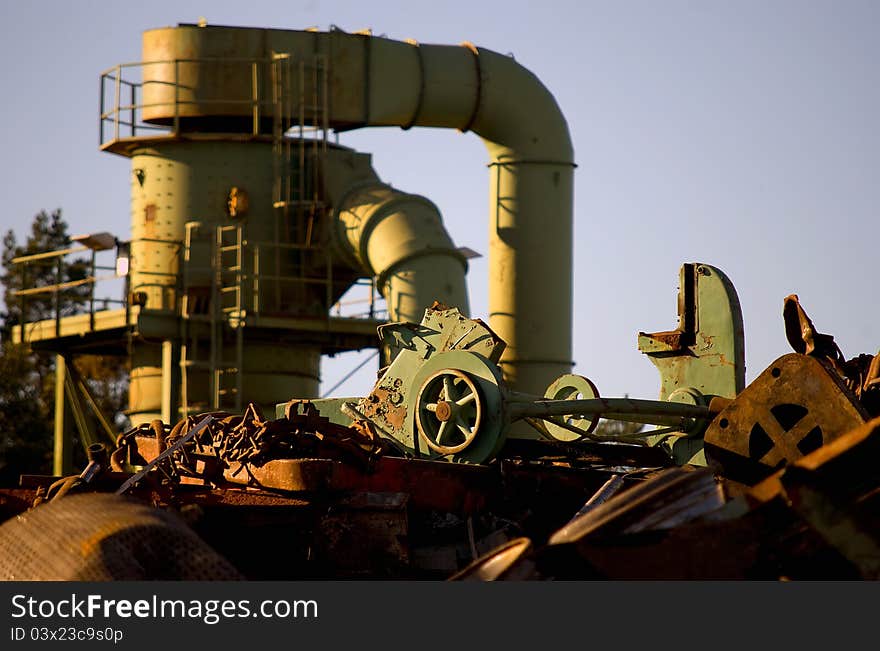 Machine behind the scrap heap works with fragmentation of the metal. Machine behind the scrap heap works with fragmentation of the metal