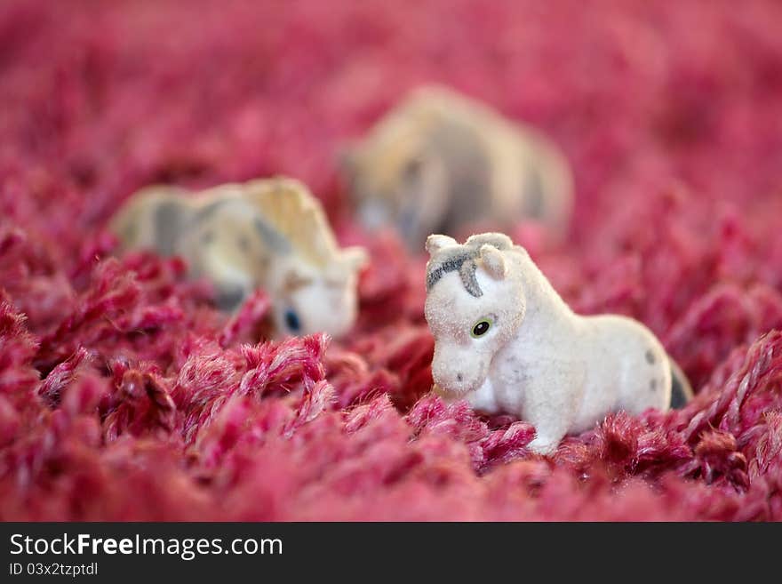 Toys horses lined up on the carpet