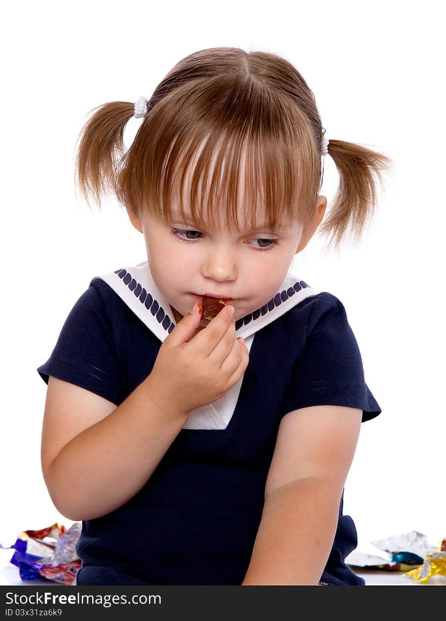 The little girl eats a chocolate. Isolated on a white background