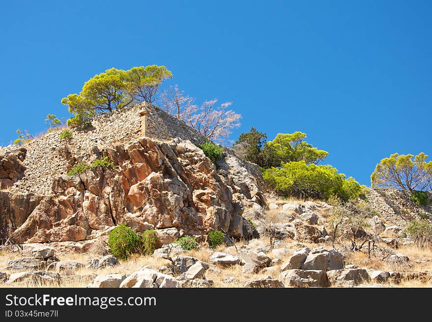 Blue sky, the old city walls, green plants, stone slope