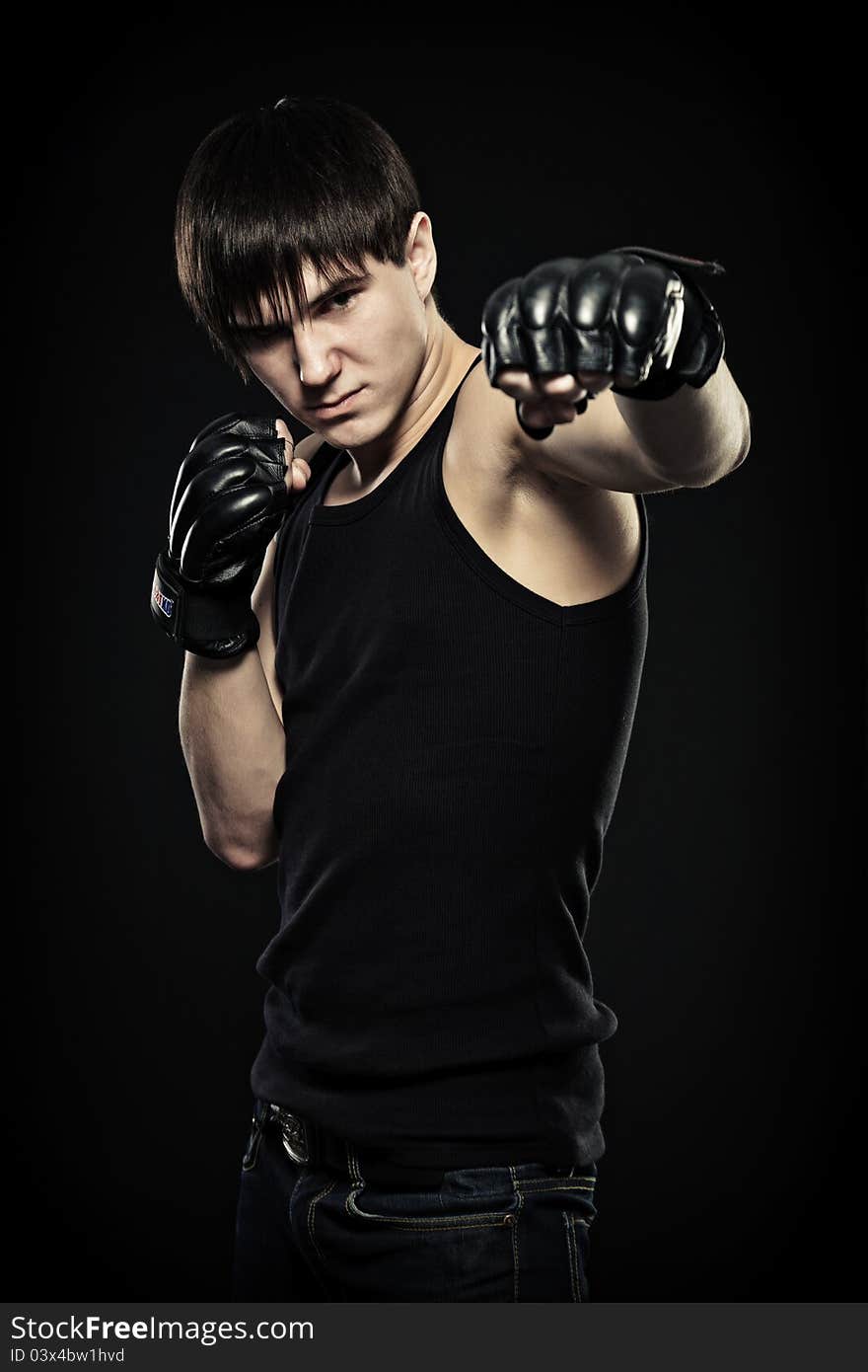 Guy in the fighting gloves, isolated black background. Guy in the fighting gloves, isolated black background.